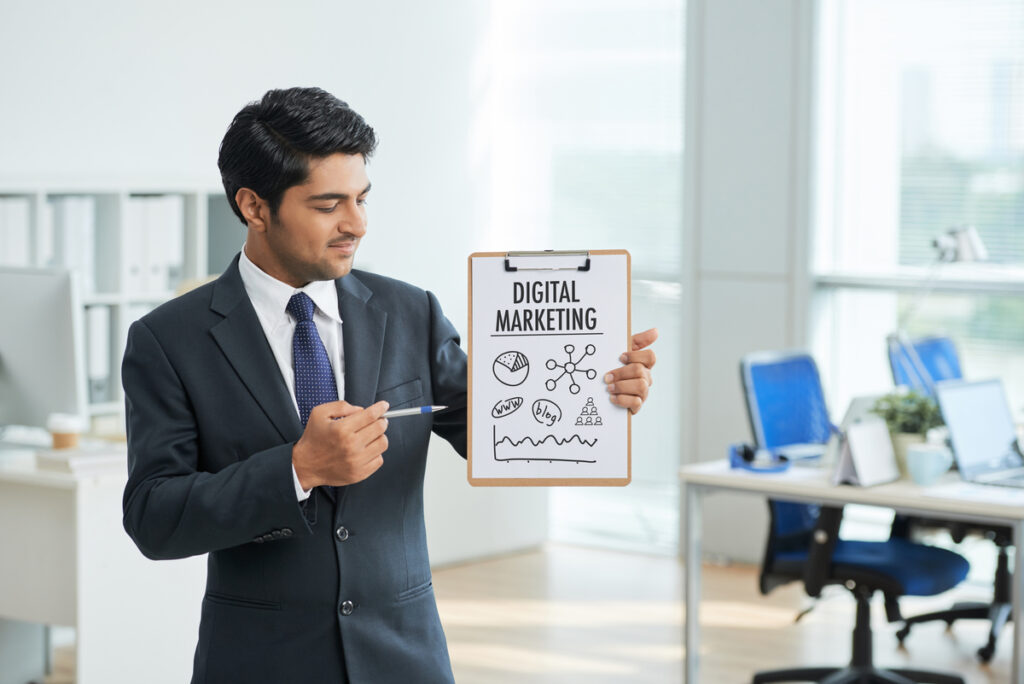 man suit standing office with clipboard pointing poster with words digital marketing